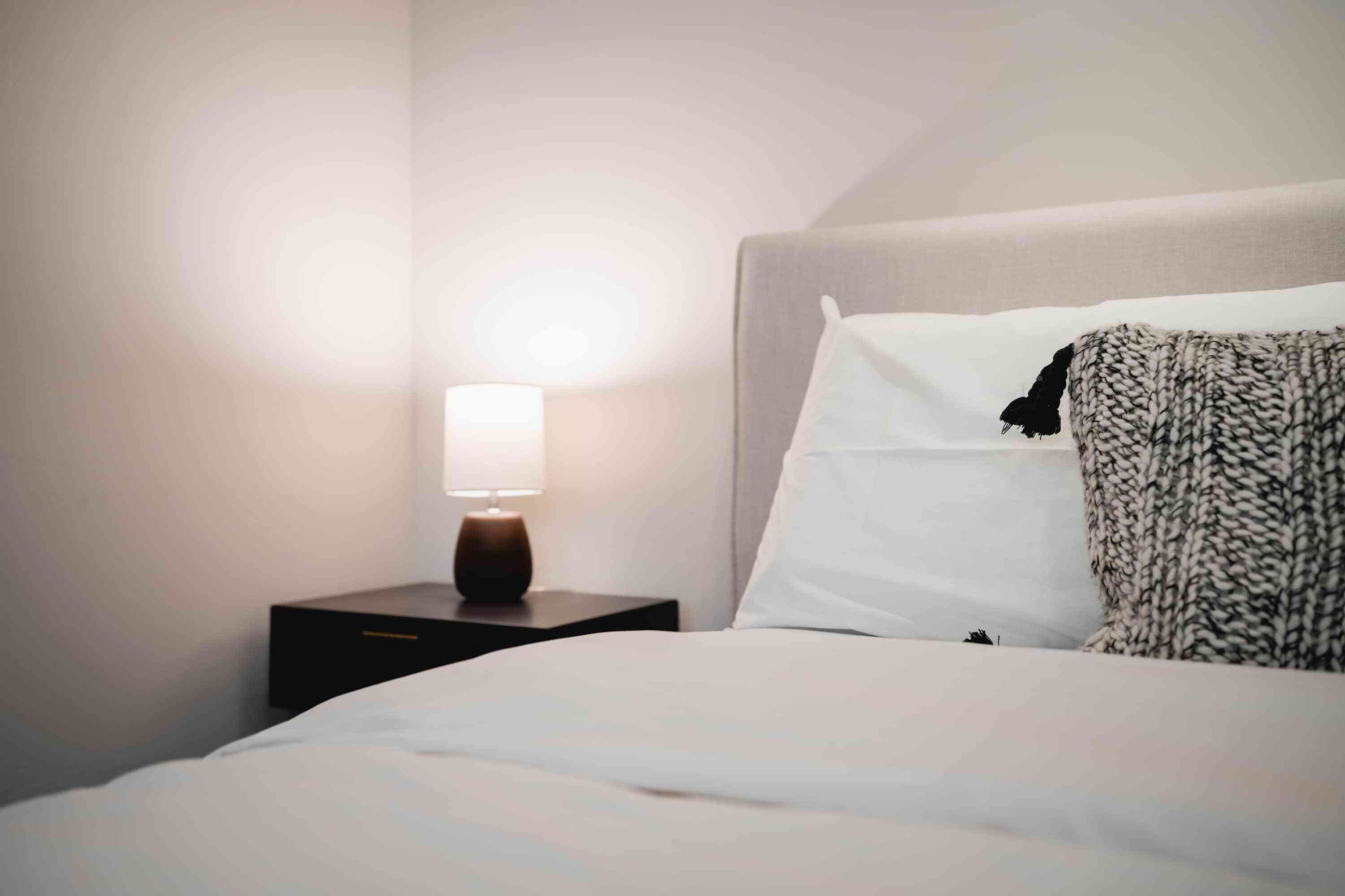 A neatly made bed with white linens and a black and white patterned throw blanket.