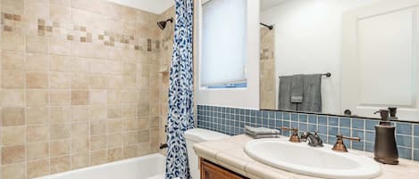 A bathroom with a bathtub, toilet, and vanity with a sink and mirror.