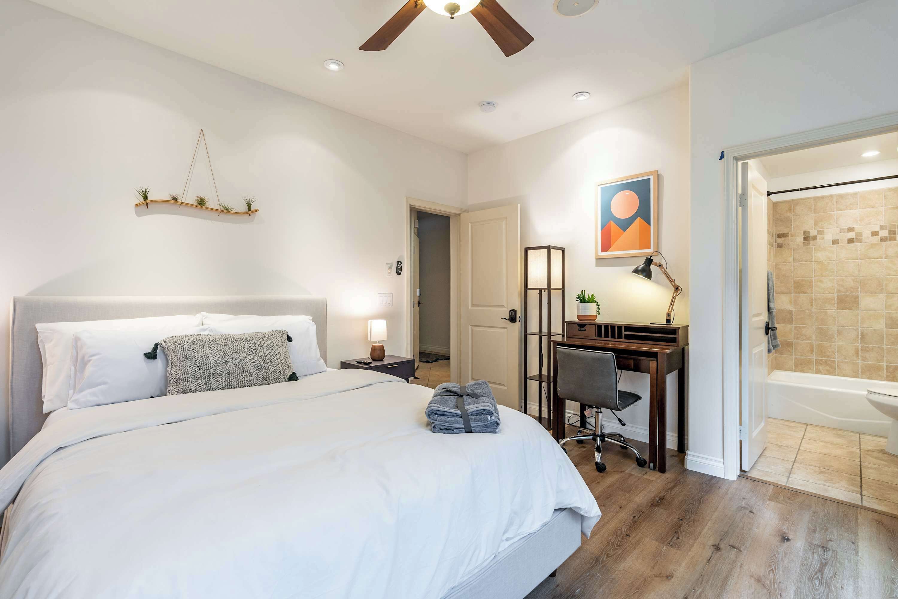 Une chambre à coucher comprenant un lit, un bureau, une chaise, ainsi qu’une salle de bain avec une baignoire et une douche.