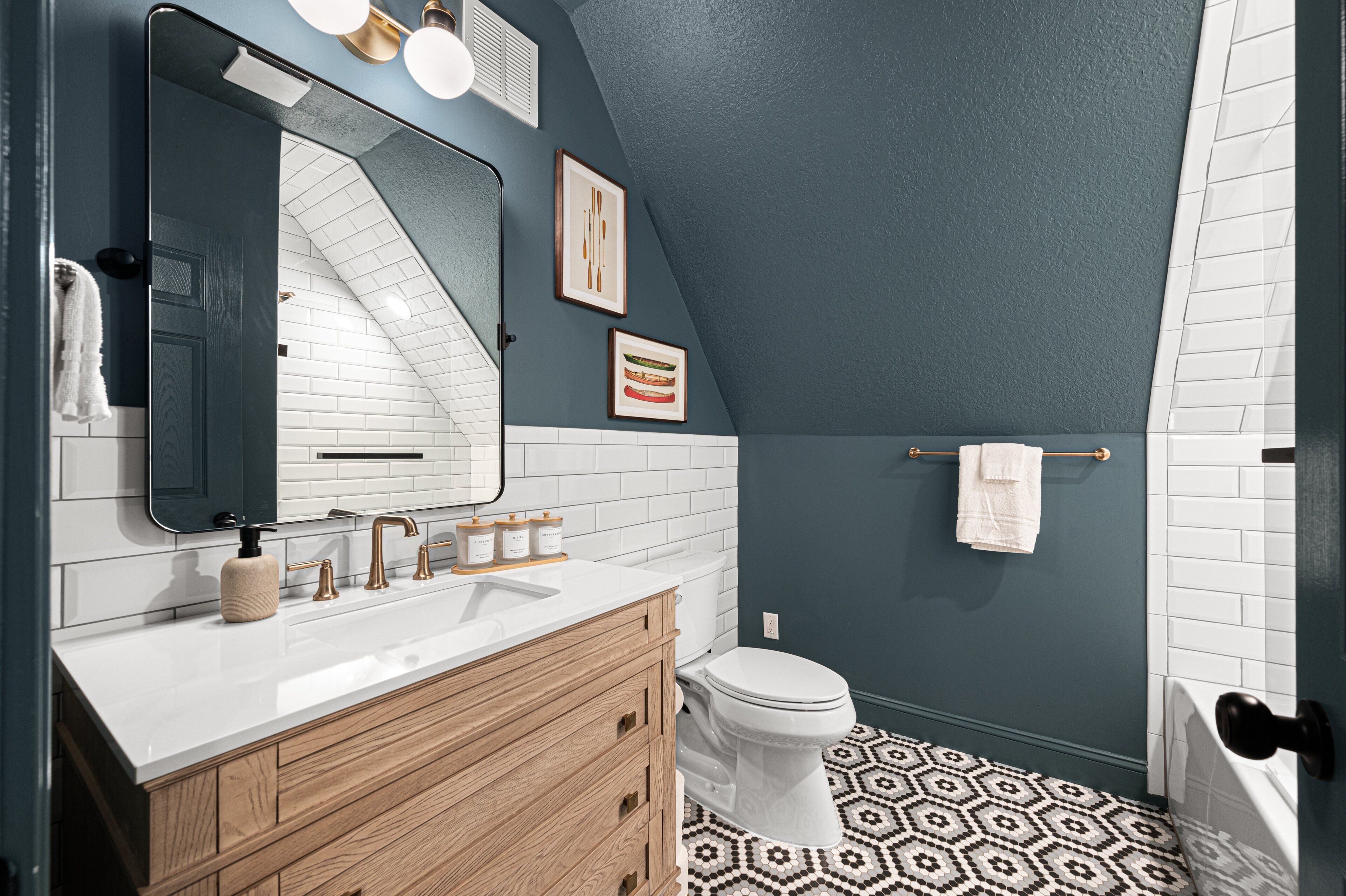 A modern bathroom with a white vanity, a large mirror, a toilet, and a shower area.