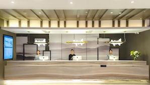 A reception desk with three staff members, a digital screen, and a modern interior design. - Atour Hotel (Chongqing)