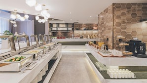 A buffet setup with various food stations, a coffee machine, and a modern kitchen in the background. - Atour Hotel (Chongqing)