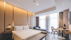 A modern hotel room with a large bed, a desk, a chair, and a sofa. - Atour Hotel (Chongqing)