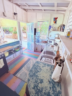 Una cocina con piso a rayas de colores, un lavamanos, un microondas y un dispensador de agua.