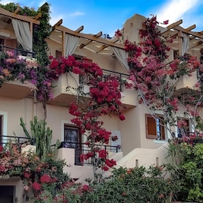 A multi-story building with balconies adorned with flowering plants and vines.