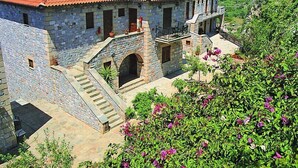 A stone house with a red-tiled roof, a stone staircase, and a small balcony. - Vardia Apartments (West Mani)