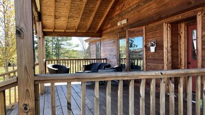 A wooden cabin with a covered porch, a red door, and a sign that reads "Hog Hunter". - Nolia Cabin in the Little River Valley (Nashoba)