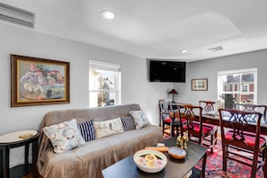 A living room with a sofa, dining table, chairs, and a TV. - Sweet Retreat (Marblehead)