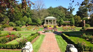 Un jardín con un pabellón, césped cuidado y estatuas.