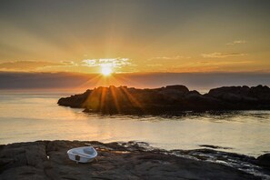 A boat on a rocky shore with the sun setting in the background. - Riverview (Beverly)