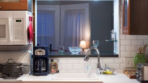 Una cocina moderna con microondas integrado, cafetera y una ventana con cortinas.