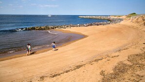 A sandy beach with a rocky breakwater and calm sea.