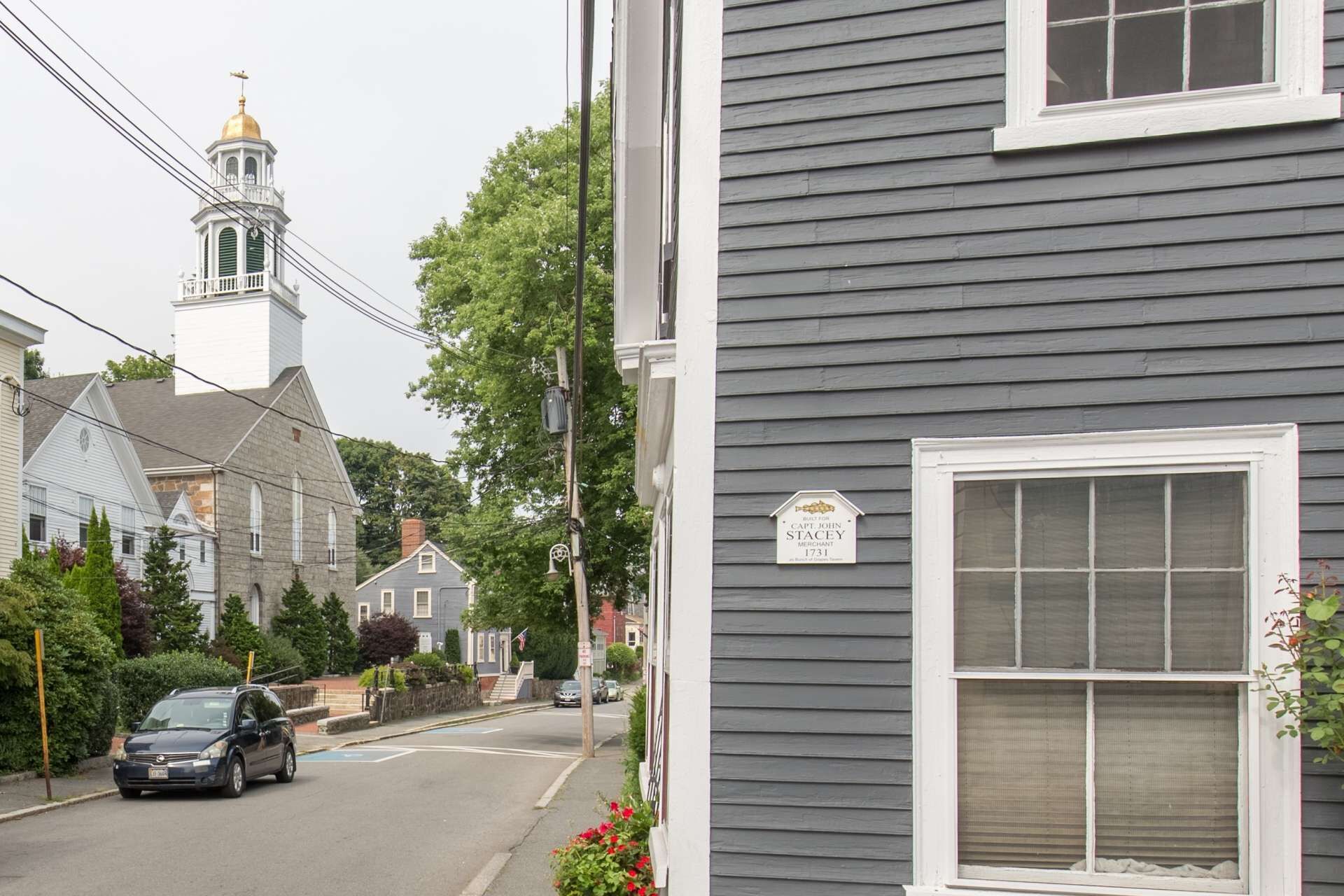 Una strada residenziale con una casa che espone una targa con il nome di Capt. John Stacey, un mercante del 1731.