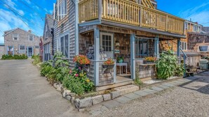 A wooden house with a porch, stone steps, and flower beds. - Bell Buoy (Rockport)