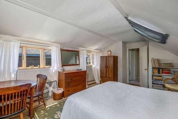 A bedroom with a bed, wooden dresser, chair, and a bookshelf.
