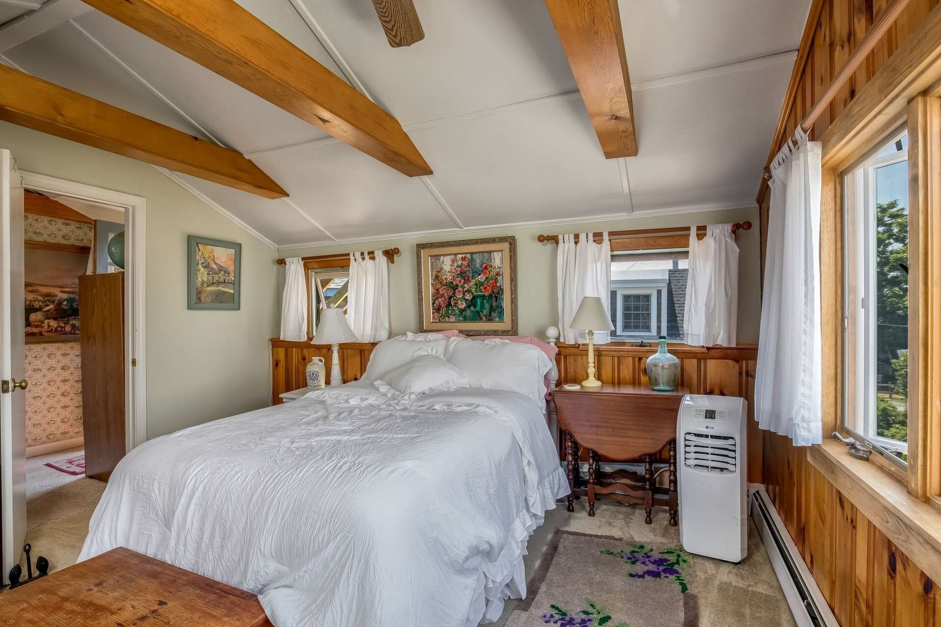 A bedroom with a bed, a desk, a chair, a radiator, and a window.