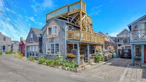 A two-story wooden house with a balcony, surrounded by other houses. - Bell Buoy (Rockport)