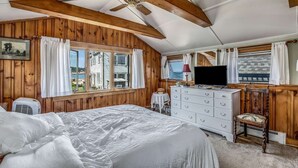 A bedroom with a bed, dresser, TV, and windows with curtains. - Bell Buoy (Rockport)