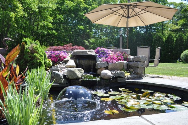 A garden with a pond, rocks, and colorful flowers.