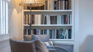 Un coin lecture confortable avec un fauteuil et une bibliothèque remplie de livres.