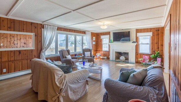 A cozy living room with wooden paneling, a fireplace, a television, and comfortable seating. - Blue Star (Salisbury)
