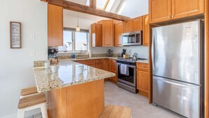 Une cuisine moderne avec des meubles en bois, un réfrigérateur en acier inoxydable et un plan de travail en granit.