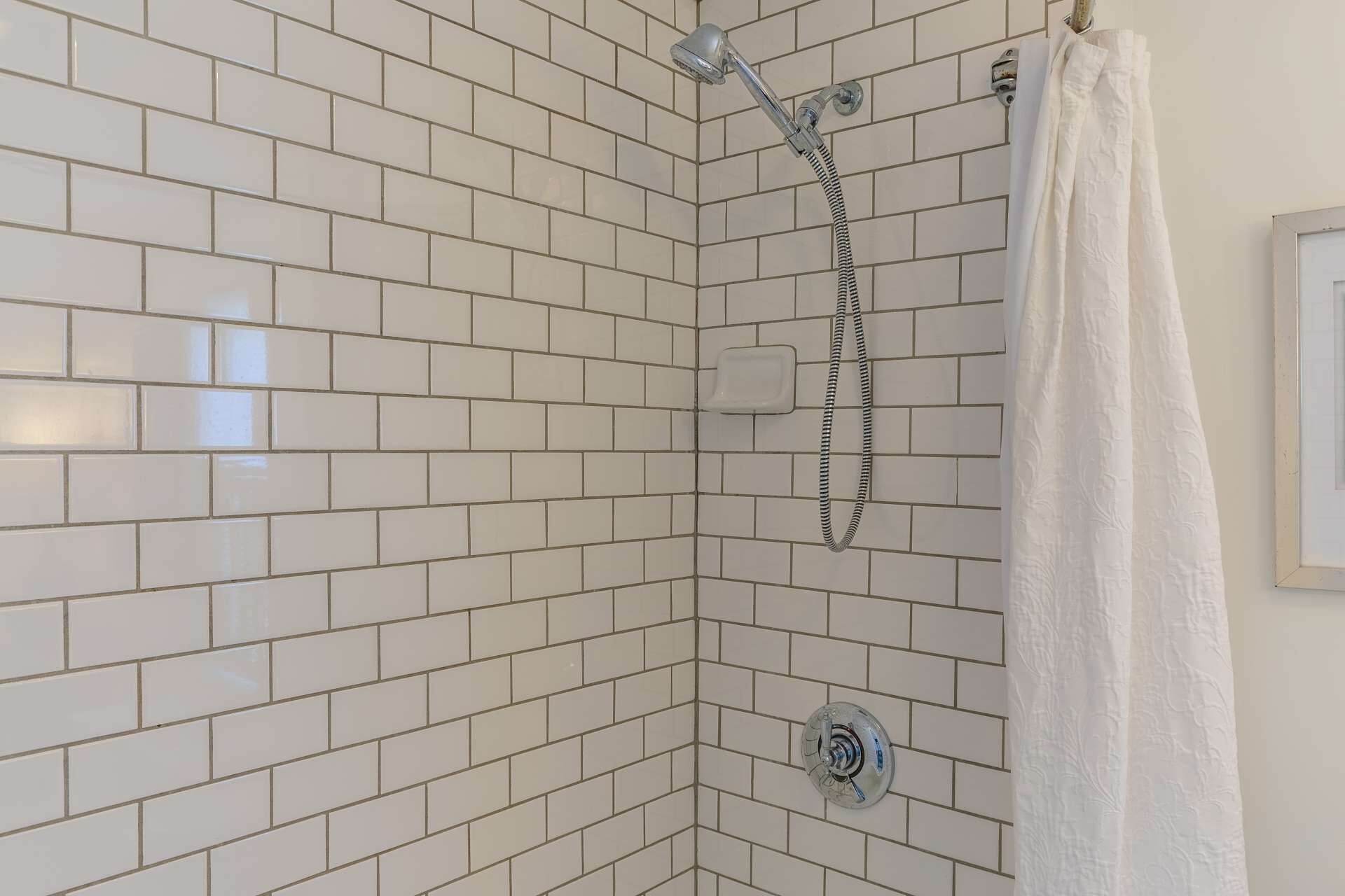 Une douche avec un pommeau de douche amovible et un porte-serviettes.