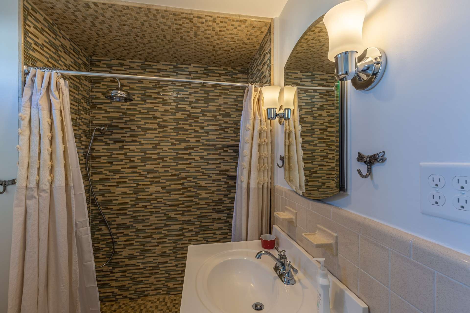 Une salle de bain avec une douche, un lavabo et un miroir.