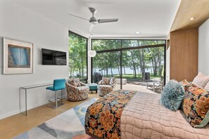 Un dormitorio moderno con una cama grande, un escritorio y una zona de estar con sillas.