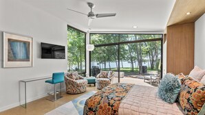 A modern bedroom with a large bed, a desk, and a seating area with chairs.