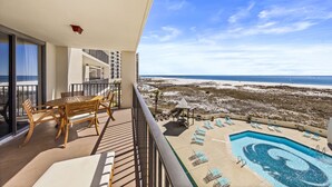 Un balcone con piscina, poltrone prendisole e vista sulla spiaggia.
