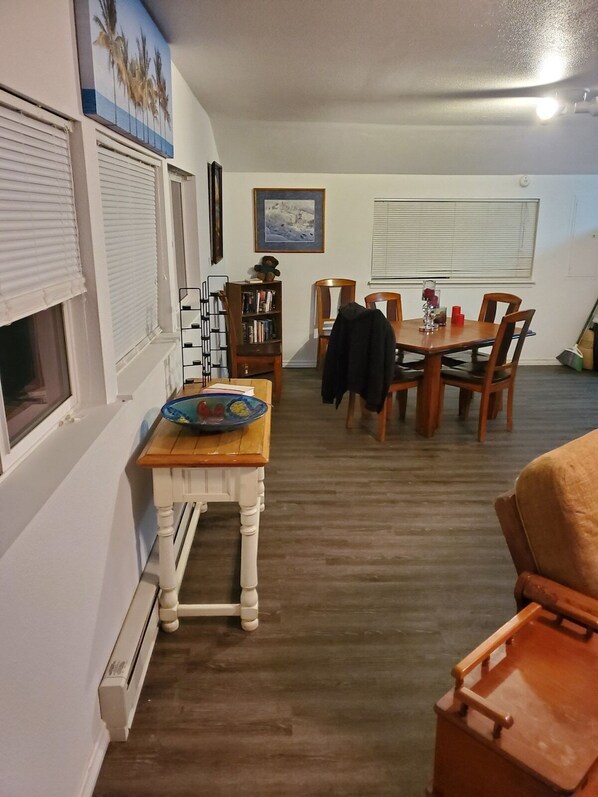 A dining area with a wooden table and chairs, a bookshelf, and a framed picture on the wall.