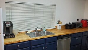 A compact kitchen with a sink, a coffee maker, a toaster, and a dishwasher.