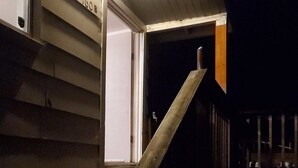 A wooden staircase leading to a porch with a white door labeled "JCOB".