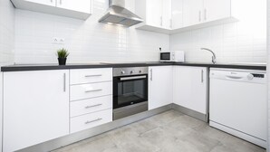 A modern kitchen with white cabinets, a stainless steel range hood, a built-in oven, a microwave, and a dishwasher. - Spacious, Central Apartment – Ideal for families (Salou)