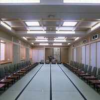 A conference room with long tables, chairs, and ceiling lights.