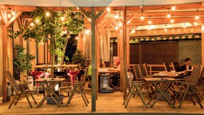 An outdoor dining area with wooden tables and chairs, string lights, and a sign indicating Japanese dining. - Yudanaka Onsen Shimaya (Yamanouchi)