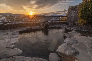 A stone hot spring with a wooden fence and a view of distant mountains at sunset. - Yudanaka Onsen Shimaya (Yamanouchi)