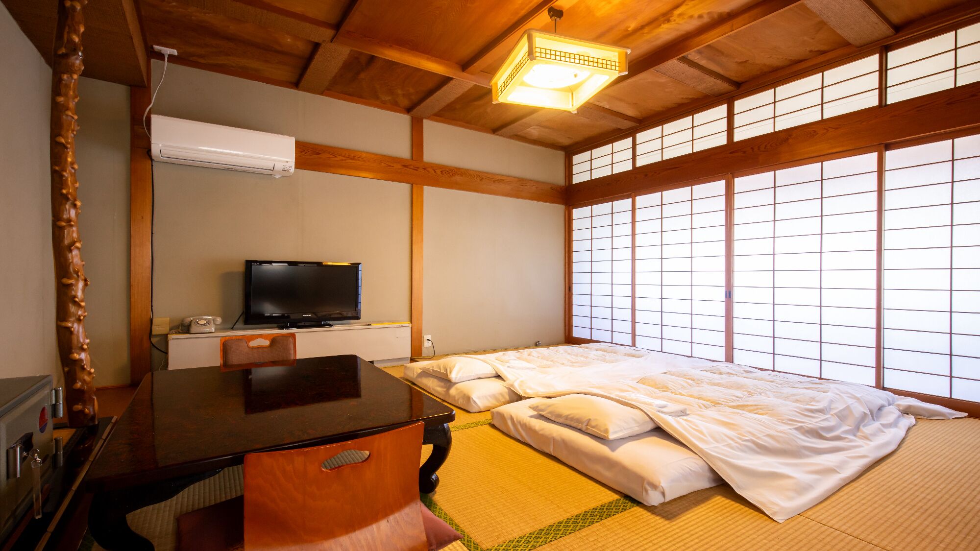 Een traditionele Japanse kamer met tatami vloeren, een bed, een televisie en een bureau.