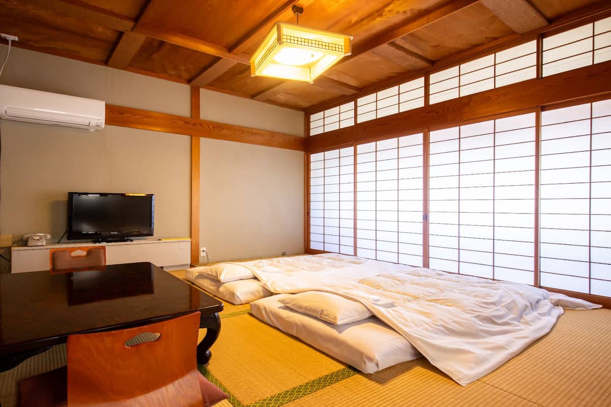 Een traditionele Japanse kamer met tatami vloeren, een bed, een televisie en een bureau.
