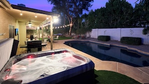 Un giardino sul retro con una vasca idromassaggio, mobili da patio e una piscina.