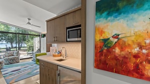 A modern kitchen with wooden cabinets, a stainless steel dishwasher, and a large window overlooking a deck. - Adults-Only Lake Peninsula Cottage w/ Pool, Pickleball & Sunset Views (Malakoff)