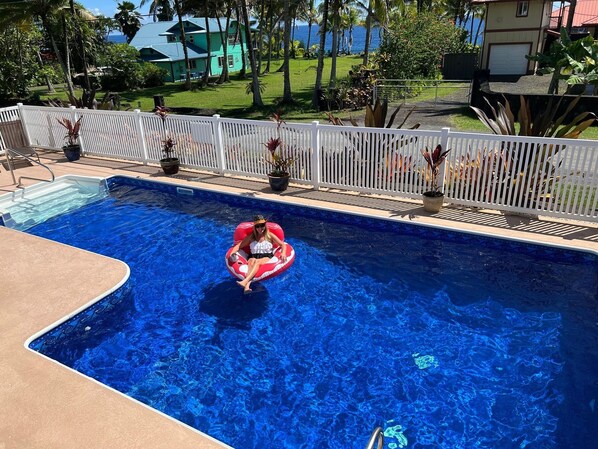 A swimming pool with a person in a red inflatable ring. - Aloha Suite: Watch Whales, Breakfast included at Ala Kai Bed and Breakfast (Keaau)