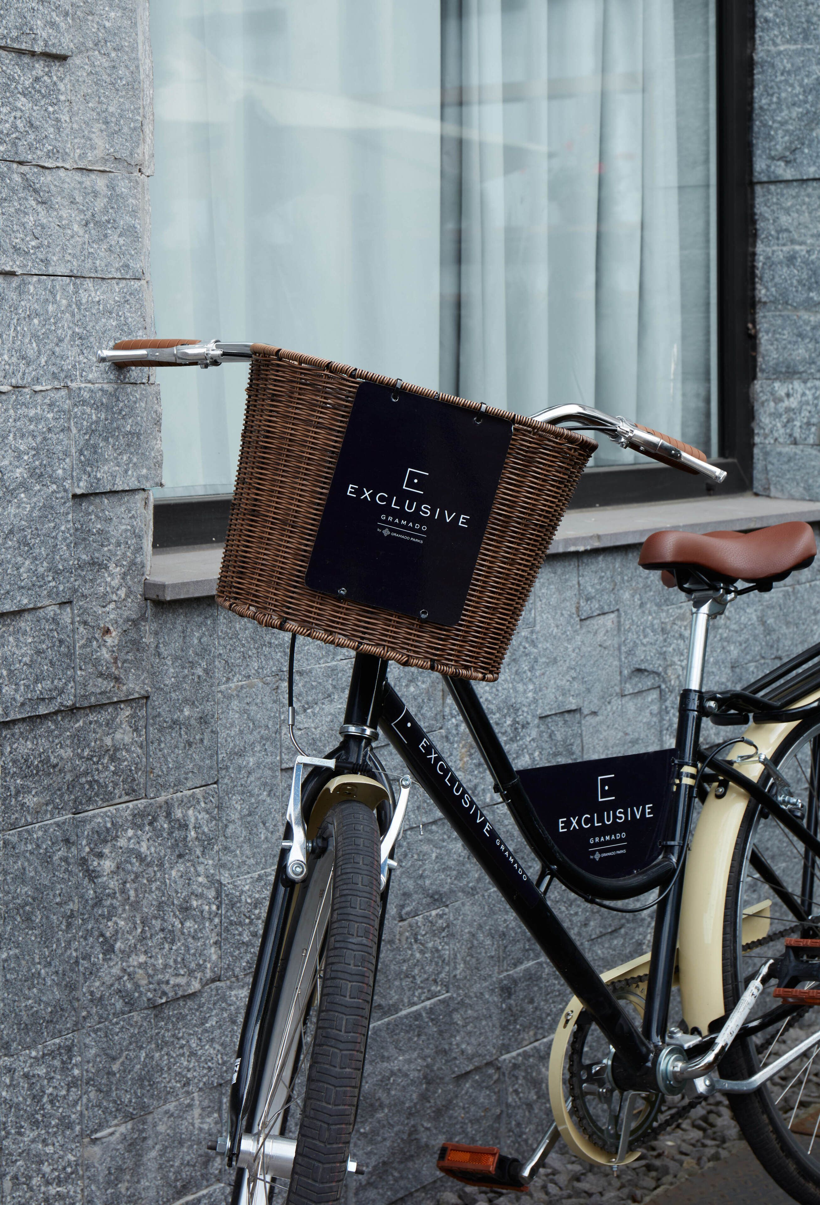 Een fiets met een rieten mandje aan de voorkant, waarop 'EXCLUSIVE GRANADA' staat.