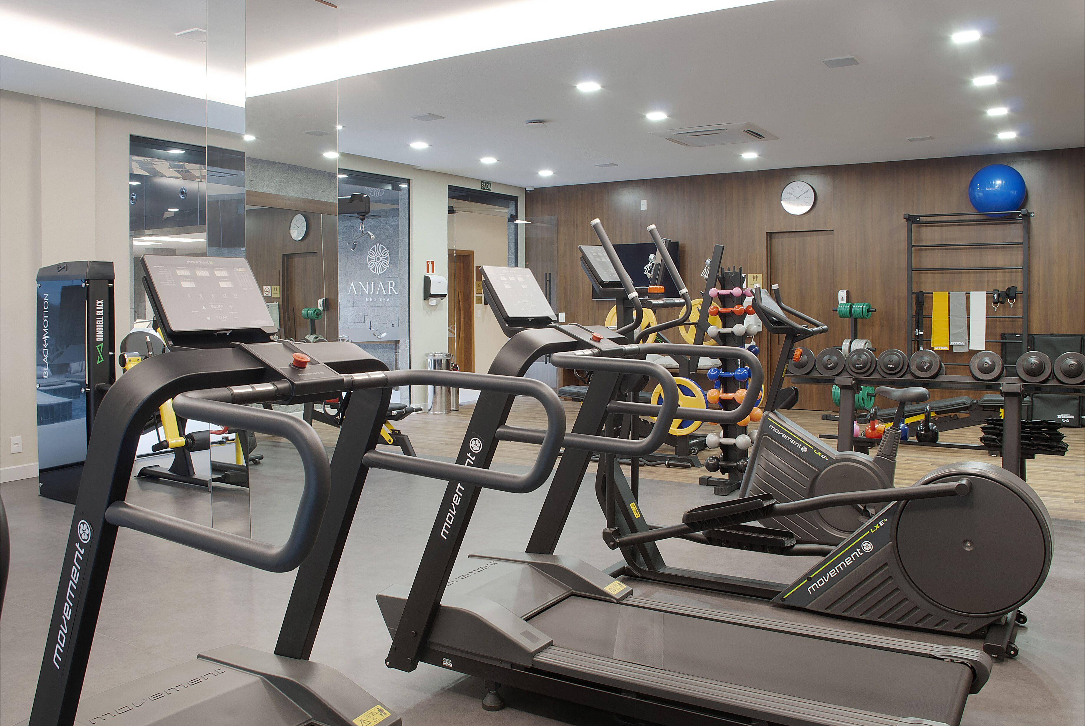 Una palestra con tapis roulant, ellittiche e diversi pesi.