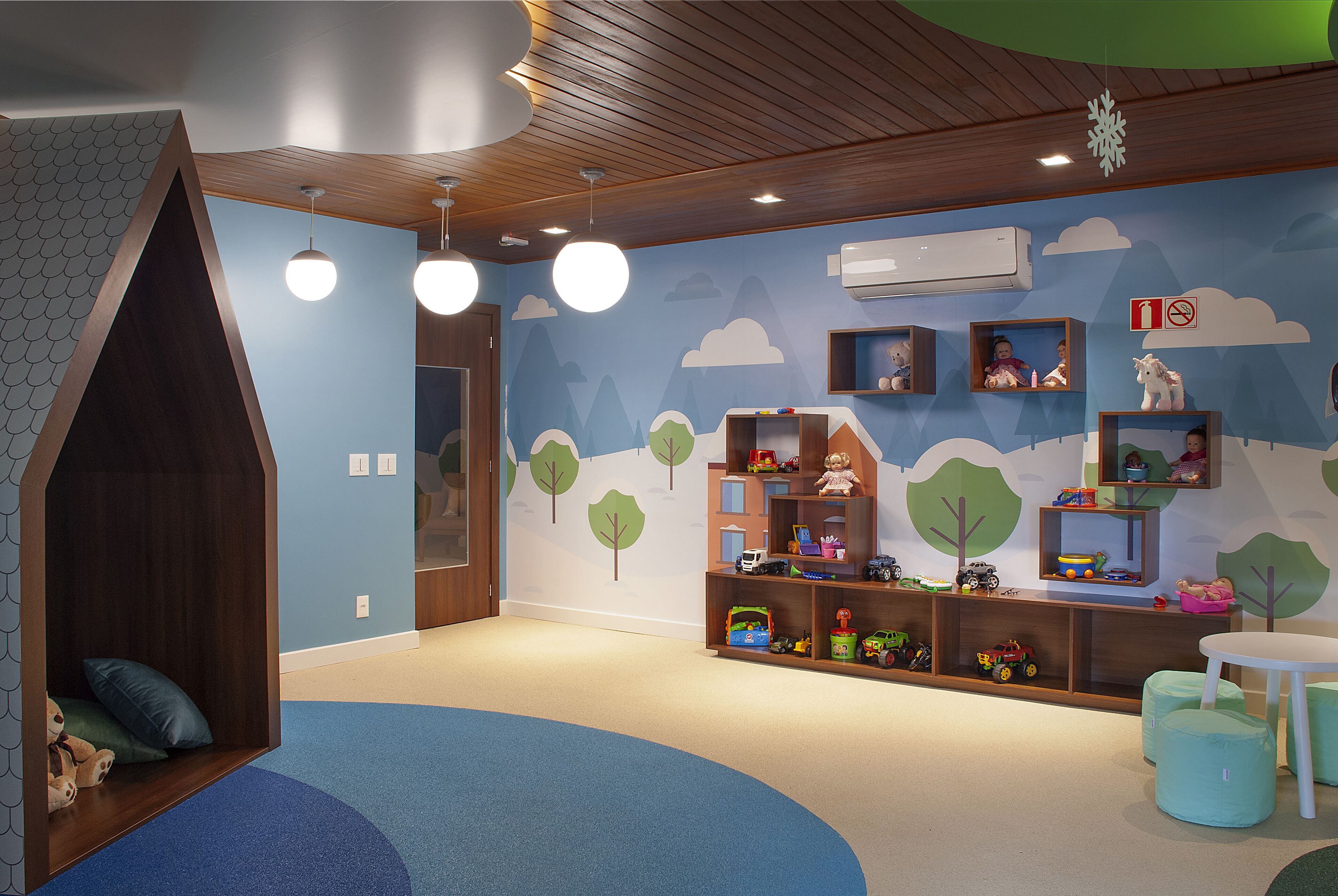 A children's playroom with a wooden playhouse, shelves with toys, and a wall mural.