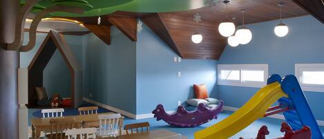 A children's play area with tables, chairs, a slide, and a rocking horse.