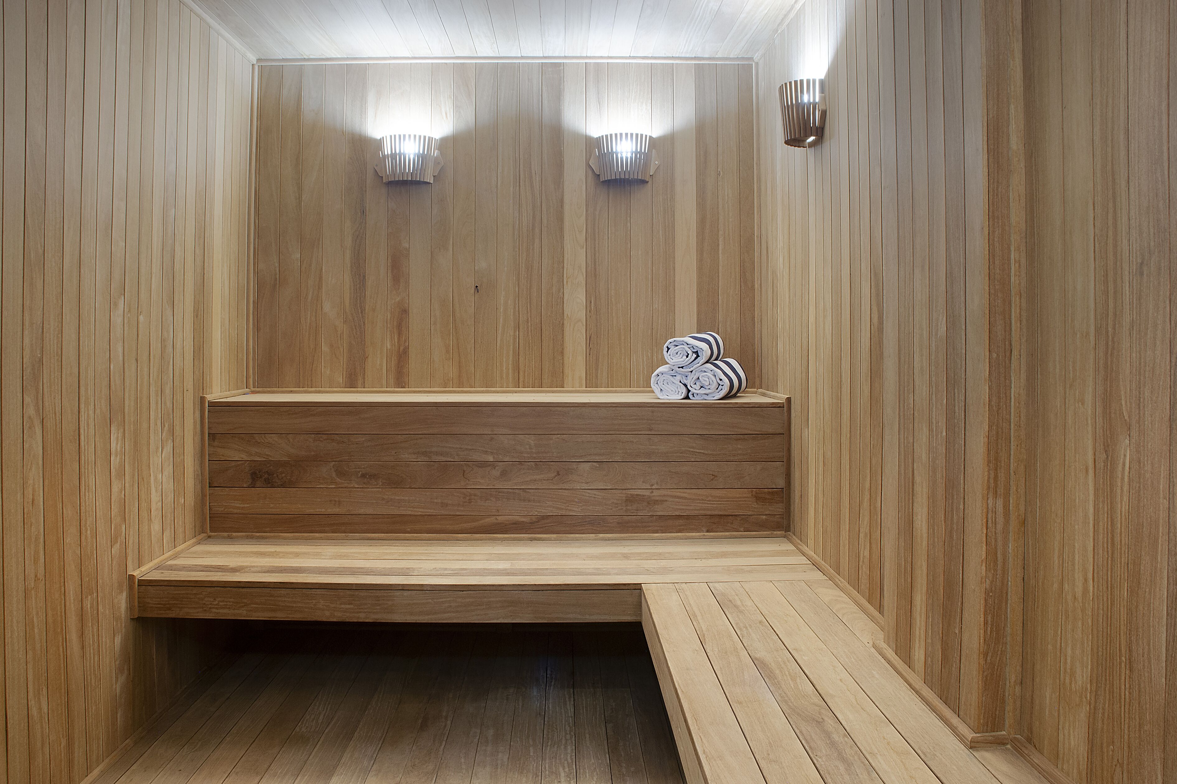 Una sauna de madera con bancos y luces fijadas en la pared.