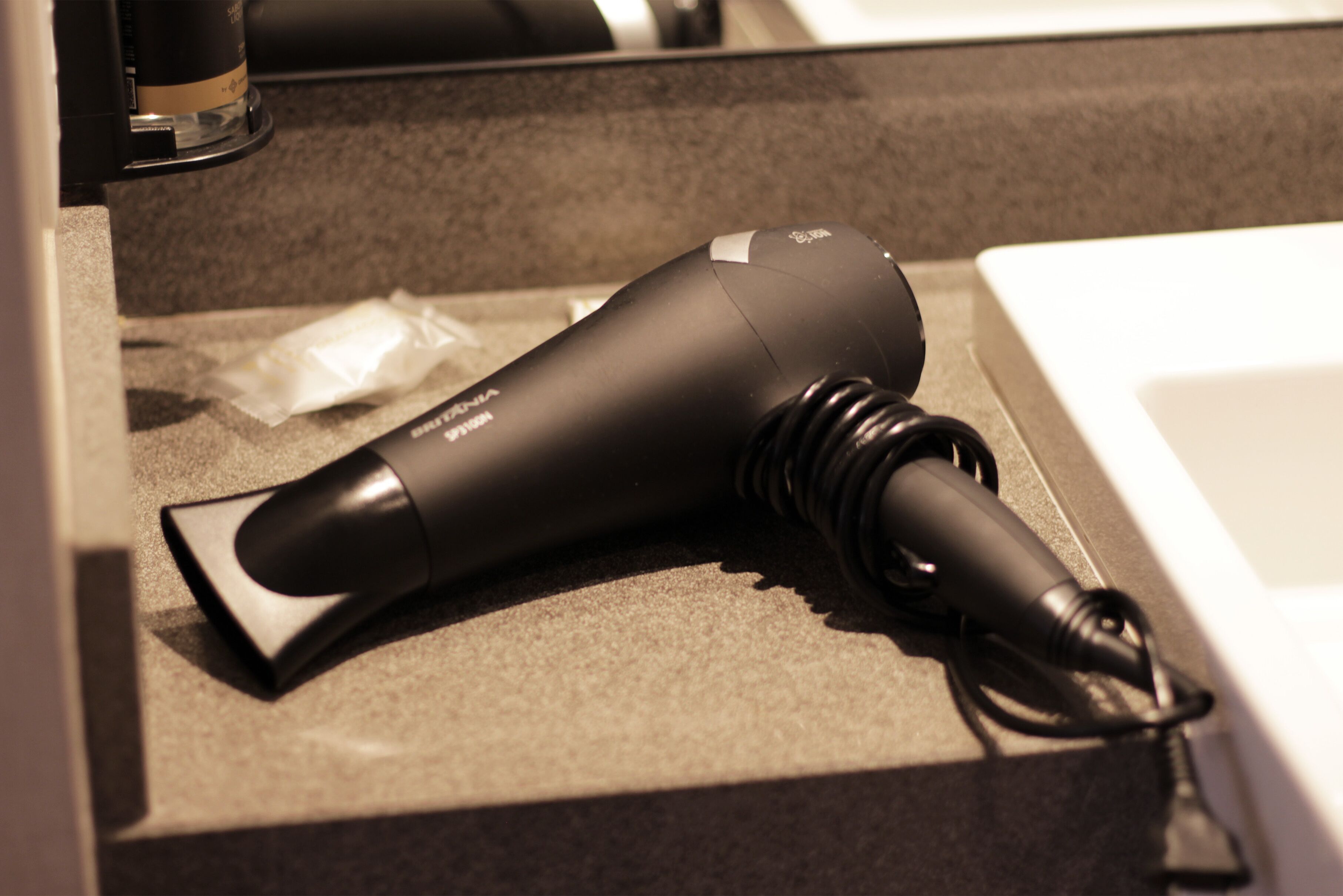 A hair dryer on a countertop next to a sink.