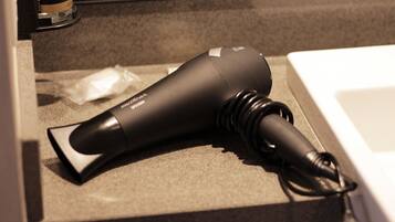 A hair dryer on a countertop next to a sink.